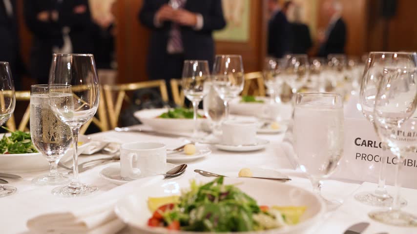 Elegant banquet dinner table setup with sparkling crystal glasses, fine dining plates, and professional catering at a luxury formal event or corporate gala.

