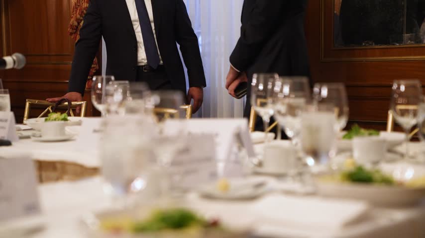 Elegant banquet dinner table setup with sparkling crystal glasses, fine dining plates, and professional catering at a luxury formal event or corporate gala.
