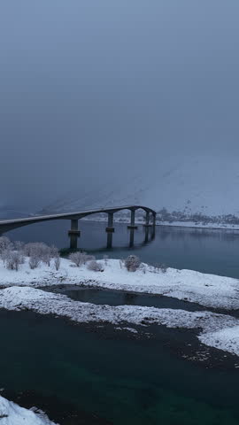 Aerial view of snowy Norwegian bridge and foggy landscape