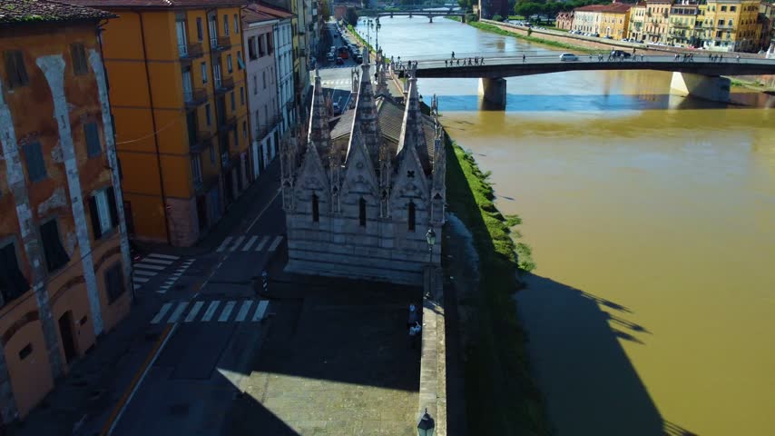 Aerial view of the gothic church of santa maria della spina on the banks of the arno river in the historic city center of pisa, tuscany
