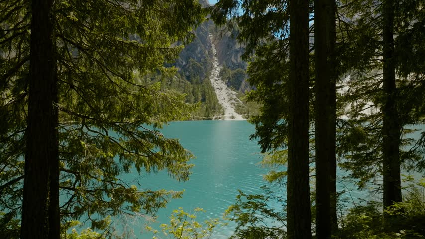 Breathtaking landscape footage of Lago di Braies in Italy featuring majestic mountains, lush pine forests, and peaceful boating on turquoise water.
