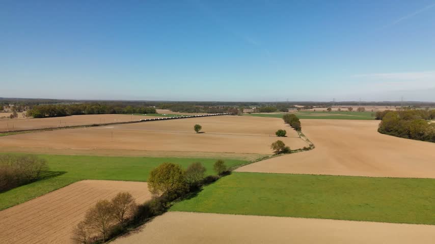 Plowed brown fields and green meadows with tree lines in spring, rural Poland