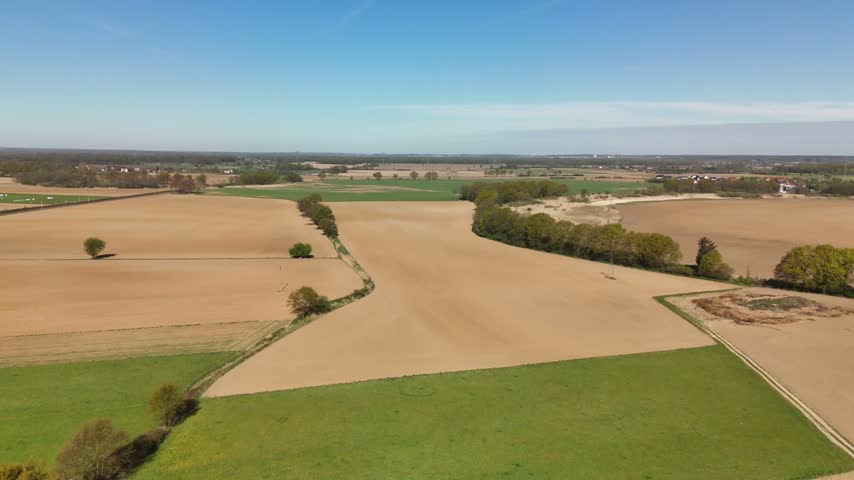 Plowed brown fields and green meadows with tree lines in spring, rural Poland