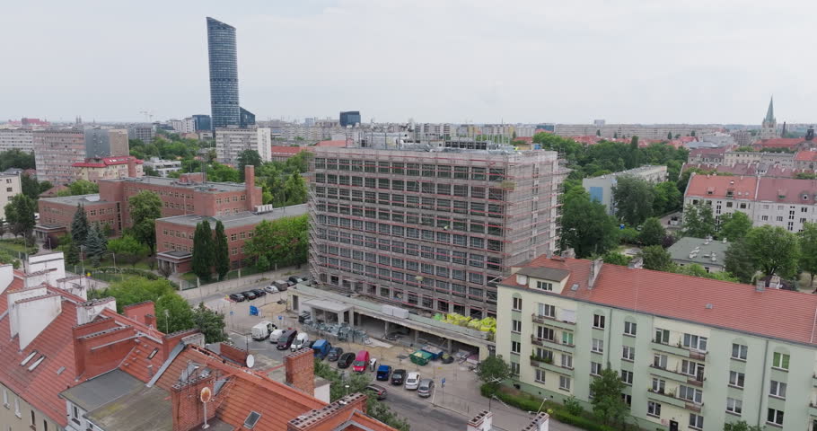 Aerial footage of a large-scale hotel renovation in Wroclaw, Poland. The mid-century building, now fully scaffolded, is being modernized into a high-end luxury hotel. Located in the heart of the city, the project blends historic charm with contemporary design, reflecting broader trends in urban redevelopment and hospitality upgrades across European cities.