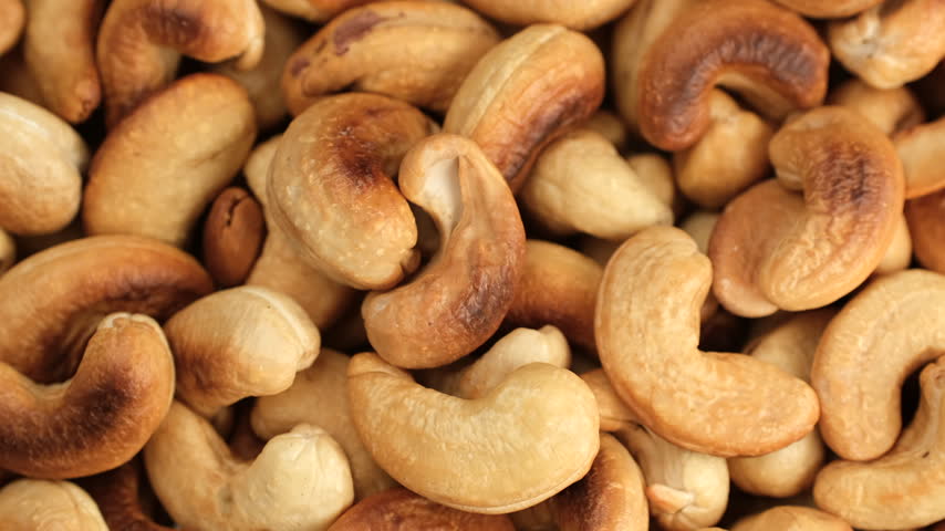 Macro heap of roasted nuts cashew in bowl, rotation. Dried cashew nuts
