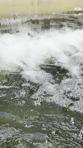 Water cascading into a pond with rippling water and white foam.