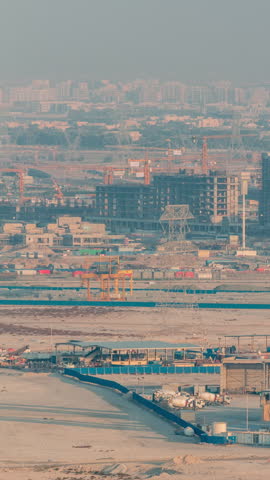 Concrete batching plant and industrial facility located in the Dubai desert with power transmission towers in the background. Daytime aerial view of urban construction development in fast motion.