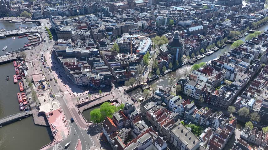 Aerial view of Amsterdam, Netherlands, showcasing historic buildings, canals, waterways and the vibrant cityscape, captured from above on a beautiful day.
