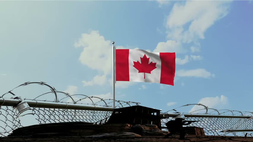 Canada Flag Waving at Military Border with Barbed Wire Fence