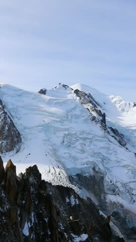 Majestic snow-covered peaks, glaciers and rugged mountain slopes of the Mont Blanc massif in the French Alps near Chamonix, France. Vertical 4K footage showcasing dramatic alpine landscapes, pristine snow, glacial formations and natural mountain scenery in clear daylight. Suitable for travel, tourism, nature, outdoor adventure and environmental projects.