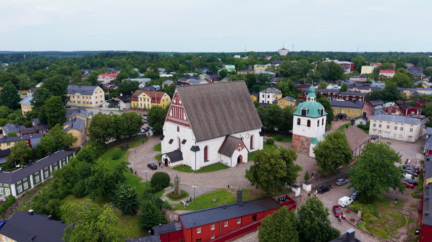 Aerial view of Porvoo Cathedral, a medieval white stone church with steep roof, surrounded by colorful historic buildings and green trees in Porvoo, Finland