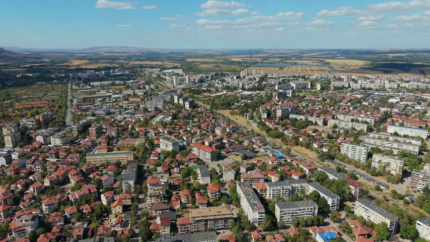 Dynamic forward camera movement descending closer to the rooftops and streets of Vratsa, Bulgaria.