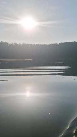 Římov Reservoir in the morning light, with calm freshwater, soft sunlight, and surrounding forested hills creating a peaceful landscape.