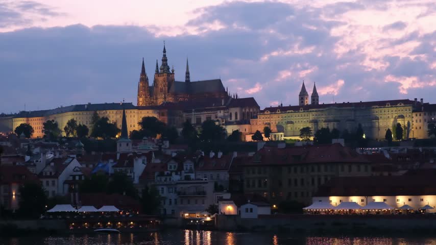 Scenic view of Prague castle and river at dusk in Czechia with illuminated old town