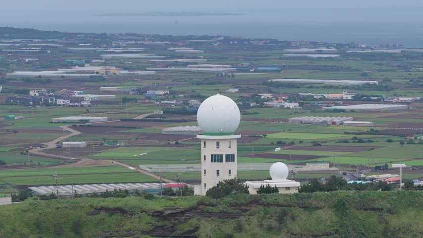 Gosan Weather Radar Observatory On Suwolbong Peak Overlooking Agricultural Fields On Jeju Island, South Korea. - aerial shot