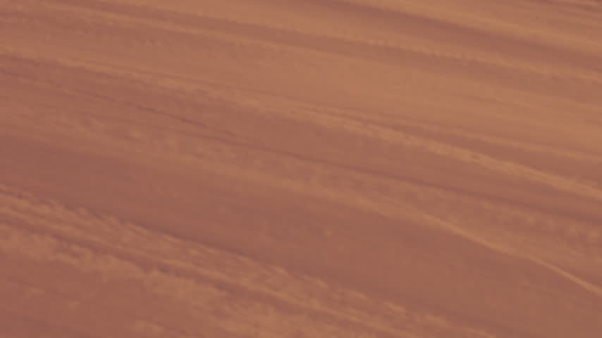 Close detail of wind-sculpted snow marked by subtle tracks in warm evening light