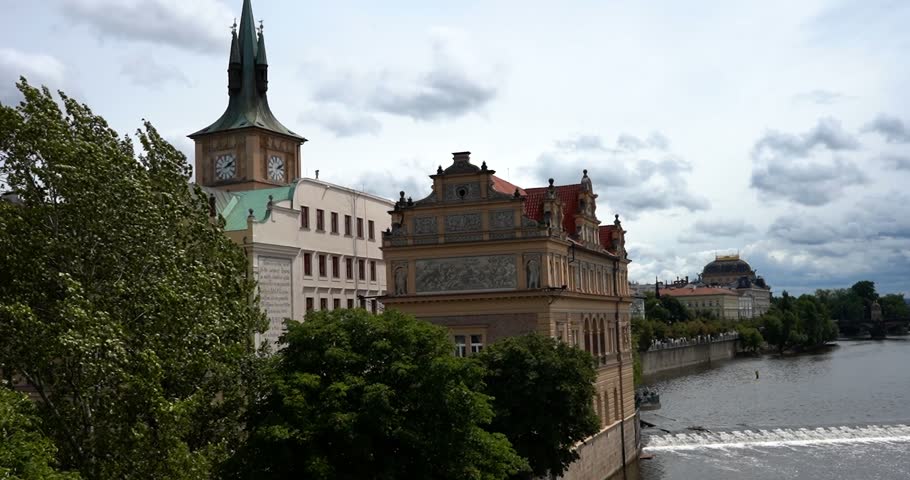 Historic buildings seen behind trees along the Vltava River in Prague, Czechia