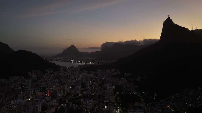Aerial view of Rio de Janeiro at dawn with Christ the Redeemer silhouetted on Corcovado mountain.