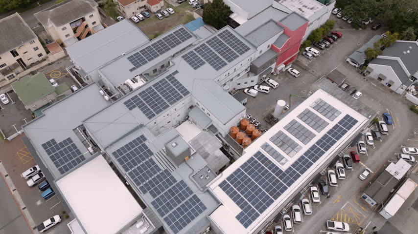 Compact South African hospital complex with rooftop solar arrays, orange water tanks, and busy parking lots seen from above.