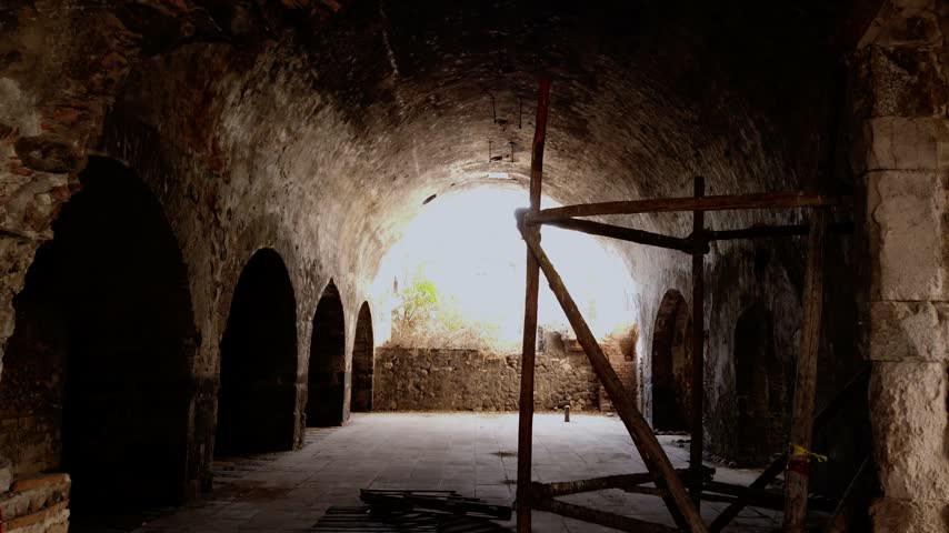 Historic vaulted chamber featuring weathered stone walls and repeated arched openings. A wooden support structure stands inside the preserved heritage museum in Mexico.