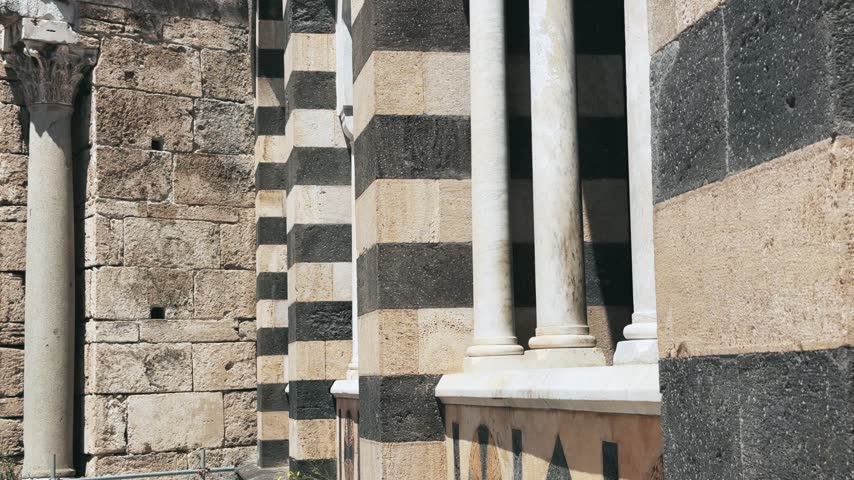 A happy woman enjoys the vibrant atmosphere and architectural beauty from a window of the historic Cathedral of Saint Andrew in Amalfi, Italy, capturing an authentic travel experience.