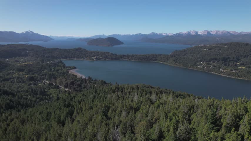 4K drone aerial view of Lake Nahuel Huapi from Cerro Campanario in Bariloche, Río Negro, Argentina. Deep blue waters stretch across the Patagonian landscape surrounded by forested mountains.