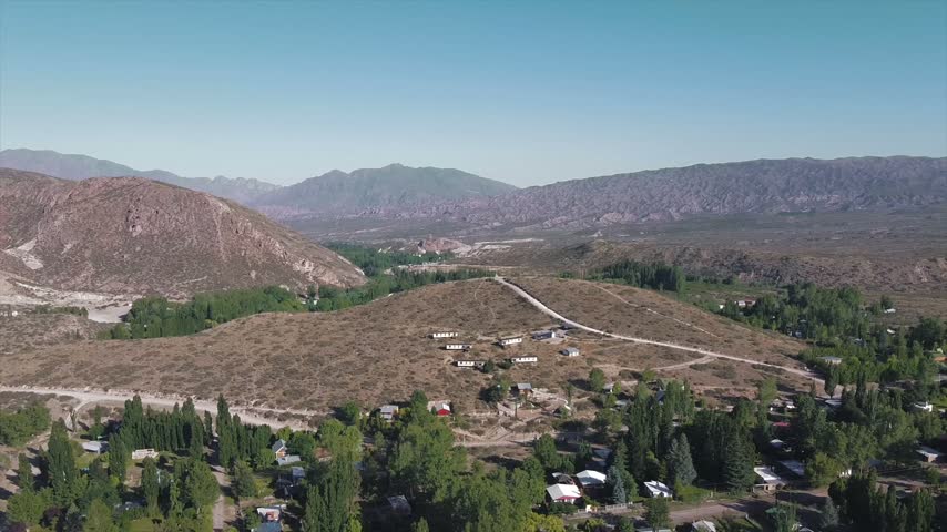 4K drone aerial view of Potrerillos, Mendoza, Argentina. Lush green Andean mountains surround scattered houses and rural landscapes in the spectacular foothills of the Andes.