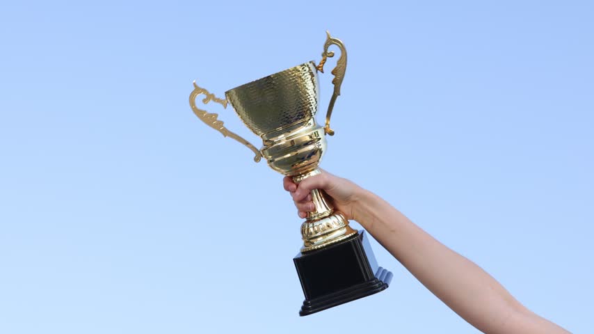 Woman with gold trophy cup outdoors, low angle view. Slow motion effect