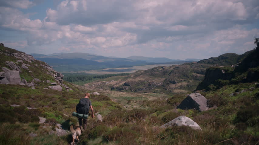 A rocky gully path winds through green gorse shrubs on the mountain trail, framed by rugged terrain.