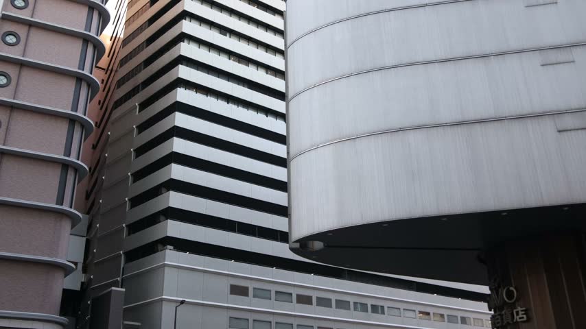 Close urban view of modern high-rise office buildings in Umeda, Osaka, Japan, emphasizing glass facades, vertical lines and contemporary architectural design
