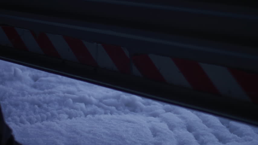 Person begins lifting a garage door to reveal groomed snow outside a mountain facility