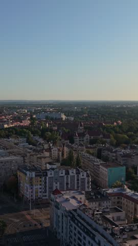 Aerial view of Wroclaw, Poland, showcasing urban landscape with historical buildings, green trees, and blue sky during sunset, highlighting city architecture and natural beauty