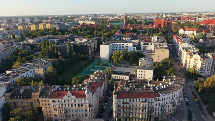 Aerial view of Wroclaw, Poland showcasing urban landscape with modern buildings, green parks, and historical architecture under clear blue sky during daylight