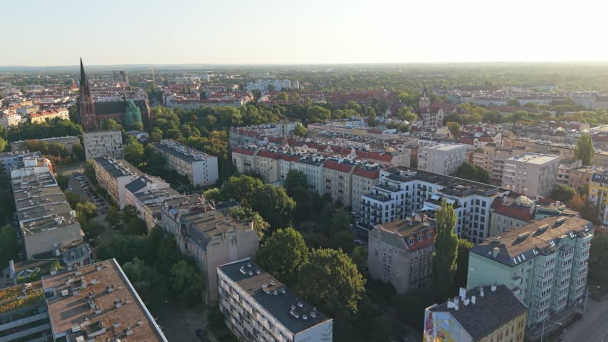 Aerial view of Wroclaw, Poland, showcasing residential buildings, lush greenery, and historical architecture under a clear sky during sunset