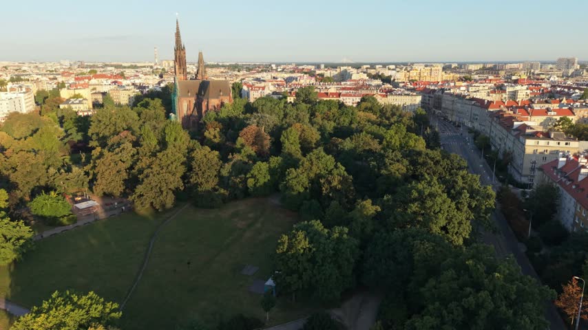 Aerial view of Wroclaw, Poland, showcasing vibrant cityscape with historic church, lush green park, and urban architecture under clear blue sky
