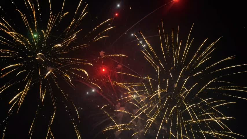 Beautiful colorful fireworks exploding in dark night sky, vibrant green and gold fireworks burst for New Year celebration, festival, anniversary, party, or holiday background.