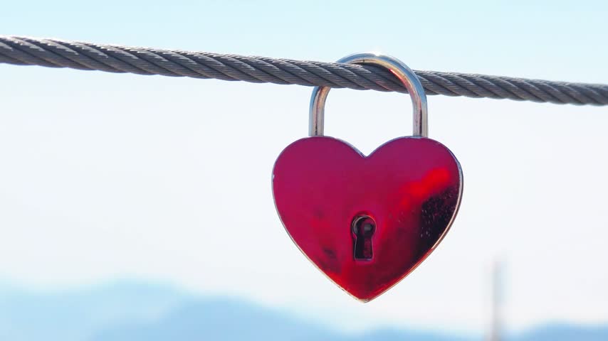 Red heart-shaped padlock hanging on a fence, symbolizing eternal love and commitment. Symbol Of Lovers. Valentine