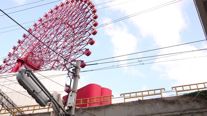 Low-angle view of the iconic red HEP FIVE Ferris Wheel in Umeda, Osaka, Japan, a distinctive urban landmark rising above the busy shopping and entertainment district
