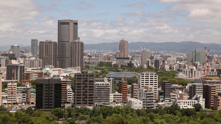 aerial Elevated panoramic view across Osaka, Japan, showing the urban skyline and green surroundings of the Osaka Castle district within the dense modern city