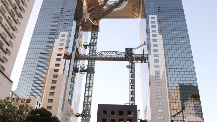 Low-angle view of the distinctive architecture of the Umeda Sky Building in Osaka, Japan, showcasing its twin towers, elevated connecting structure and modern engineering
