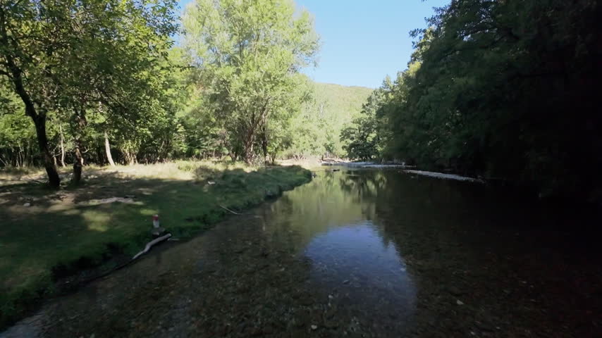 A drone rises above the forest canopy revealing the river valley.