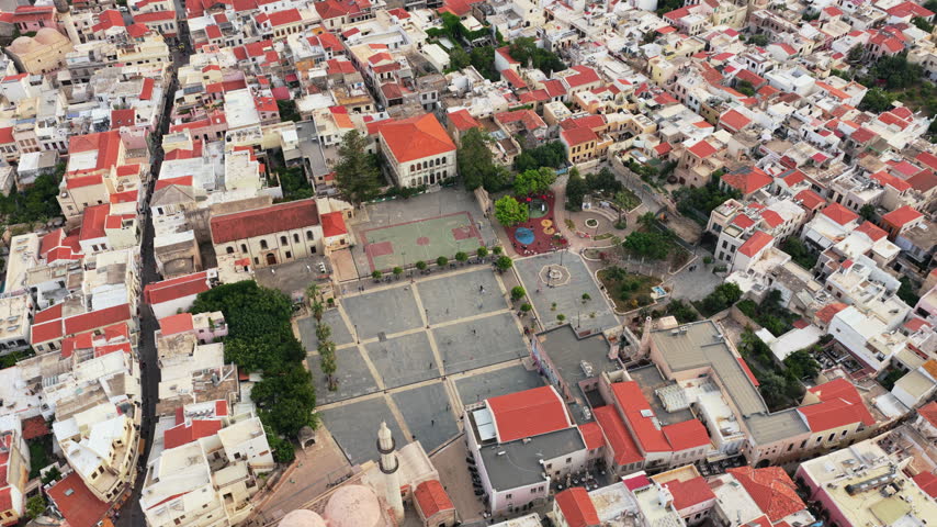 Aerial drone view of the red-roofed old town and the Neratze Mosque minaret above dense historic streets, Rethymno, Greece