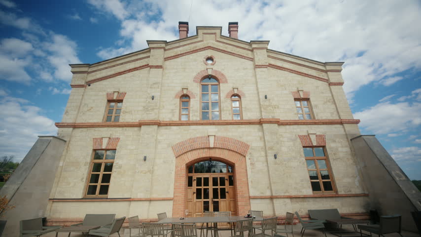 Low angle view of the historic facade of winery in Moldova, featuring stone walls, brick details, arched windows, and outdoor seating