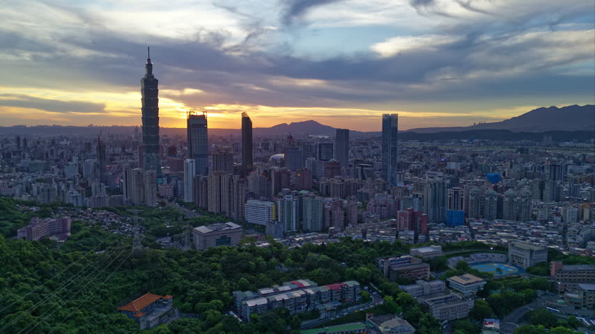 Aerial hyperlapse at night above Downtown Taipei, the vibrant capital city of Taiwan, with modern skyscrapers in XinYi Commercial District and city lights dazzling under twilight sky.