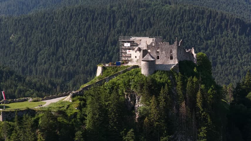 Historic ruins of Ehrenberg Castle perched on a steep, wooded hill in Reutte, Tyrol, Austria