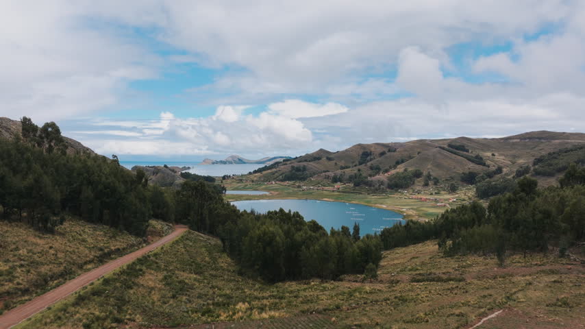 Cinematic aerial view of Lake Titicaca with sweeping blue water and the surrounding Bolivian Andes landscape