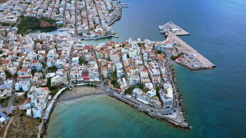 Aerial drone view of the peninsula packed with houses and its harbor, Agios Nikolaos, Greece