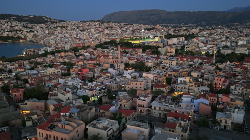 High-altitude aerial drone view of the old town with its Ottoman minaret and the illuminated city, Chania, Greece