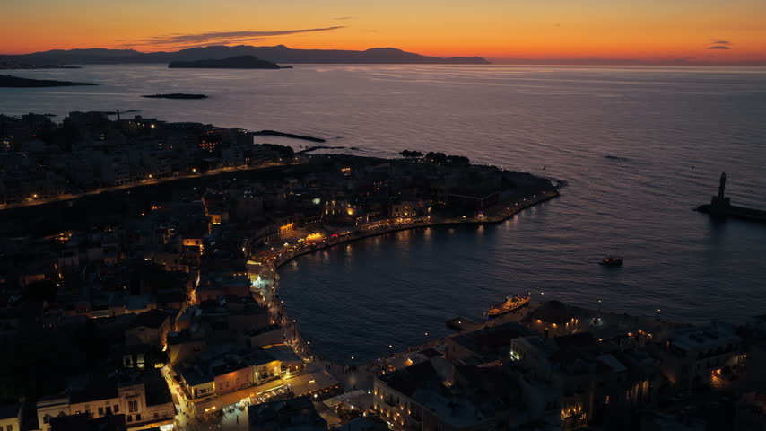 Aerial drone view of the old town and Venetian harbor with the breakwater lighthouse after sunset, Chania, Greece