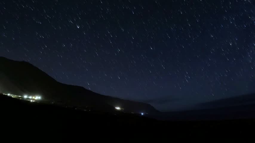 Night sky moving stars creating trails over the mountains, Island El Hierro, Canary Islands, Spain, Europe. Stunning starry night sky creating star trails over a silhouetted landscape with some passing clouds, Island El Hierro, Canary Islands, Spain, Europe. 